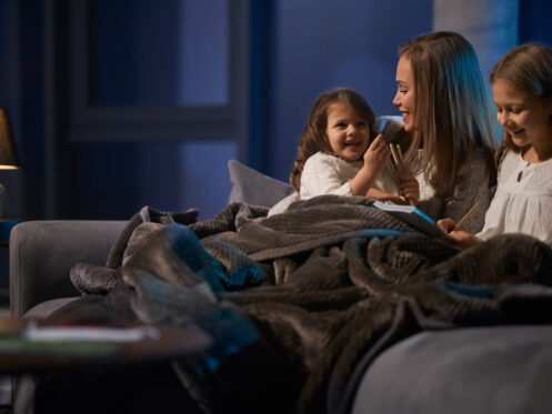 Young woman and two children relaxing under a blanket